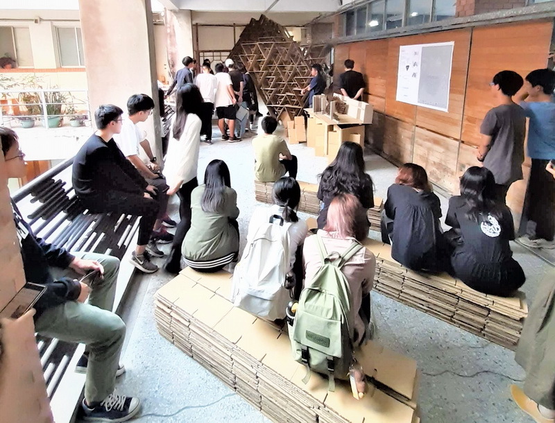 02-學生們坐在自己搭建的紙構築進行最終評圖